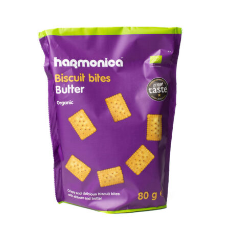 Fotografija pakiranja Harmonica Biscuit Bites s maslacem. Ljubičasta vrećica s zelenim rubom sadrži ilustraciju hrskavih organskih keksića od einkorna i maslaca. Na prednjoj strani pakiranja istaknuto je da su keksići organski, dok je u donjem dijelu navedena neto težina od 80 g. Pakiranje također nosi oznaku "Great Taste 2020" kao znak kvalitete.